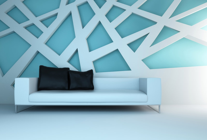 A white couch with black pillows in front of a blue wall.